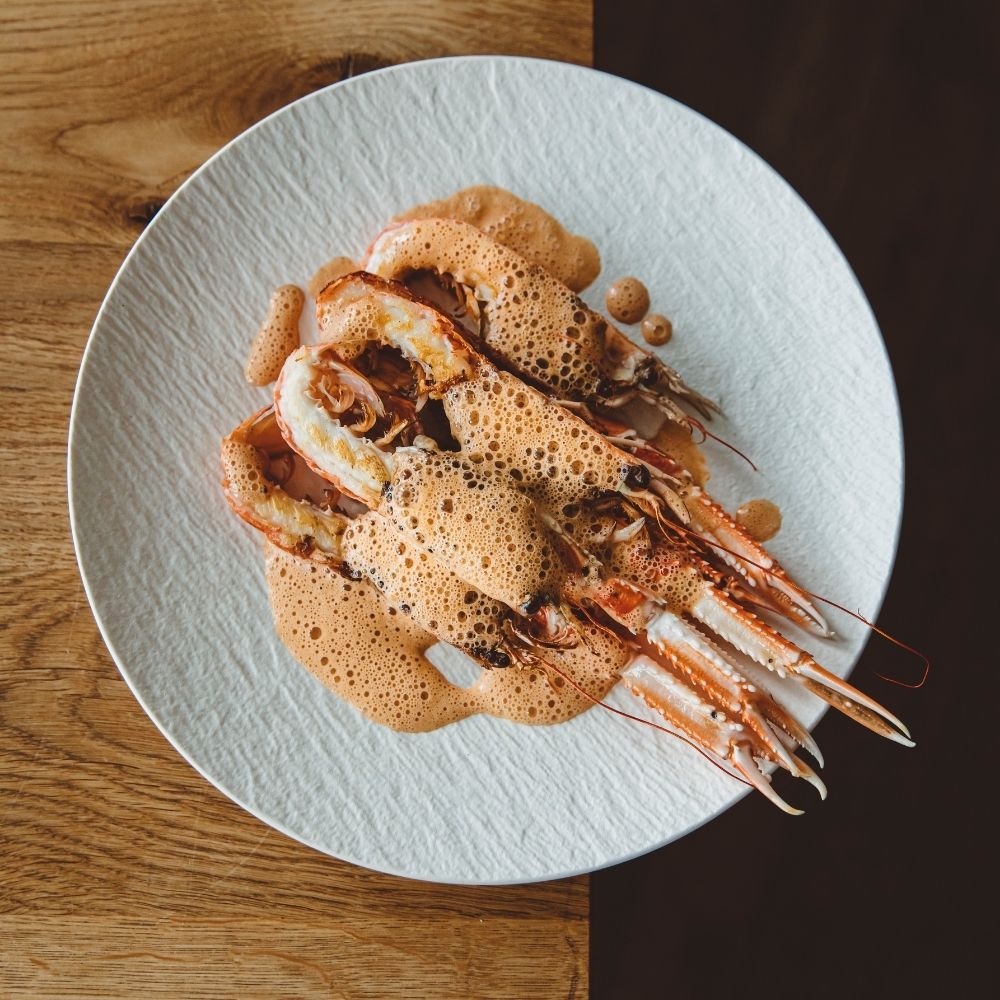 Gehalveerde Langoustine Met Bisqueschuim Op Een Wit Bord Van Bovenaf Gefotografeerd Op Een Houten Tafel