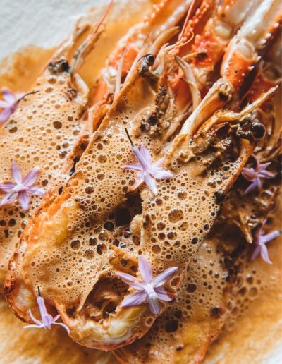 Langoustines Met Schuimsaus En Paarse Eetbare Bloemen Op Een Wit Bord Close Up