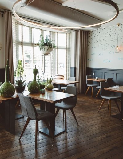 Restaurantinterieur Met Houten Vloer Groene Glazen Vazen Hangplanten Ronde Lichtarmatuur En Vissenbehang